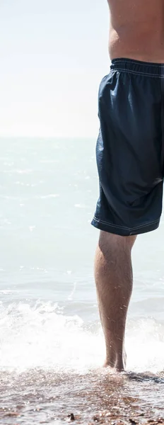 没有衬衫的男人赤脚在沙滩上走入大海 — 图库照片