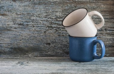 Eski yıpranmış mavi ahşap tahta üzerinde iki seramik boş Kupalar Beyaz ve mavi renk