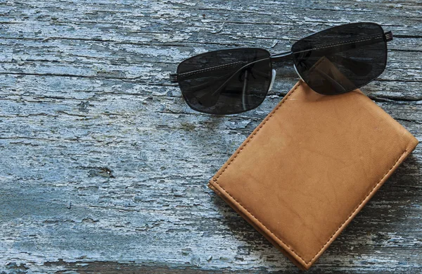 木製のテーブルの上に横たわるサングラスと革製の財布 上からの眺め — ストック写真