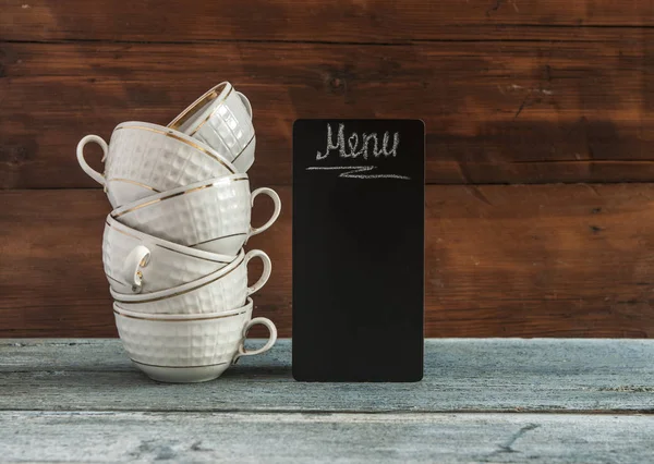 white stack coffee cups and small blackboard on wooden tabletop. Menu. Tea card. Coffee card
