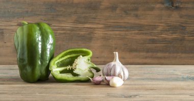 Yeşil ham biber ve ahşap arka plan üzerinde mor sarımsak