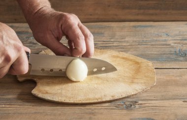 Şef tahtadan soğanları kesiyor.