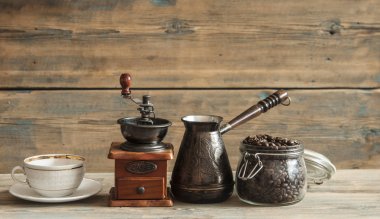 Cam kavanoz, kahve değirmeni ve jezva ahşap masa üzerinde kavrulmuş kahve çekirdekleri