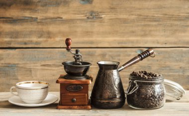 Cam kavanoz, kahve değirmeni ve jezva ahşap masa üzerinde kavrulmuş kahve çekirdekleri