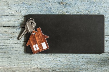 Üstten görünüm simgesi ile siyah kartı ahşap arka plan üzerindeki gümüş anahtar metniniz için evin tanıtımı veya ürün.