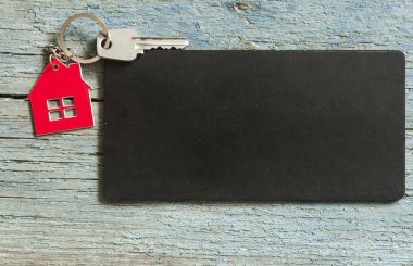 Üstten görünüm simgesi ile siyah kartı ahşap arka plan üzerindeki gümüş anahtar metniniz için evin tanıtımı veya ürün.