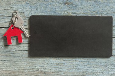 Üstten görünüm simgesi ile siyah kartı ahşap arka plan üzerindeki gümüş anahtar metniniz için evin tanıtımı veya ürün.