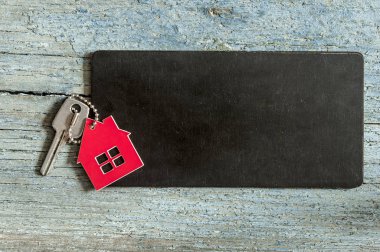 Üstten görünüm simgesi ile siyah kartı ahşap arka plan üzerindeki gümüş anahtar metniniz için evin tanıtımı veya ürün.