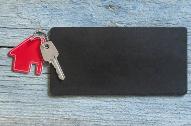 Üstten görünüm simgesi ile siyah kartı ahşap arka plan üzerindeki gümüş anahtar metniniz için evin tanıtımı veya ürün.