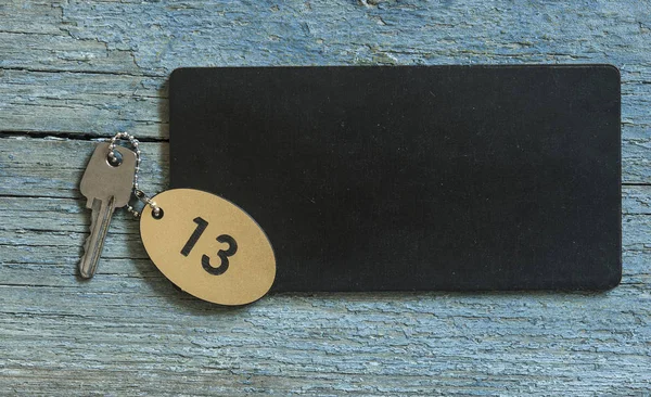 テキストの黒の基板上の木製の背景に銀の鍵と家の平面図記号を宣伝または製品 — ストック写真