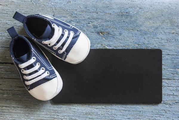 Niedliche Kleine Babyschuhe Und Schwarzes Brett Auf Hölzernem Hintergrund Für — Stockfoto