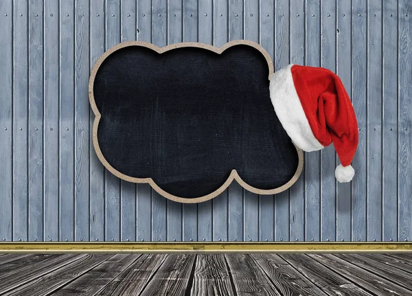 圣诞老人帽子挂在黑板上的讲话气泡超过蓝色的木墙 — 图库照片