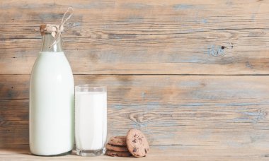 Bardak süt ve çikolata parçalı kurabiye ahşap arka plan üzerinde