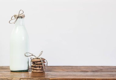 Bardak süt ve çikolata parçalı kurabiye ahşap arka plan üzerinde