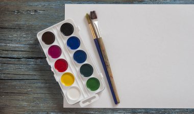 Suluboya boyalar, fırçalar ahşap antika arka plan boyama ve boş beyaz kağıt kağıda için kümesi. Üstten görünüm.