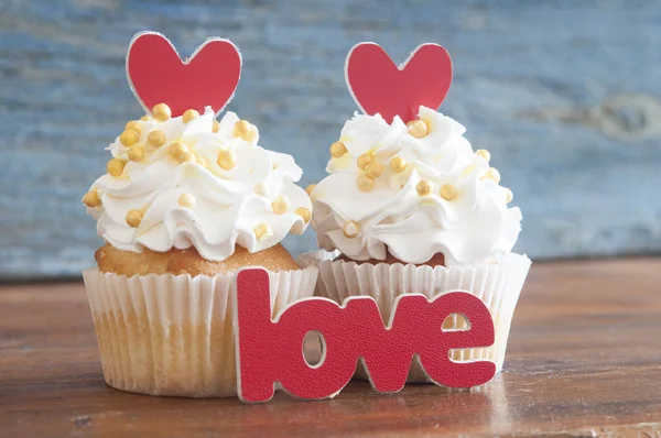 テキスト愛と木製の背景にハートの形でカップケーキ — ストック写真