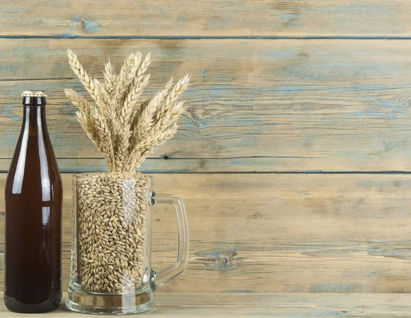 ガラスと木の板に小麦の穂とビールの瓶 — ストック写真