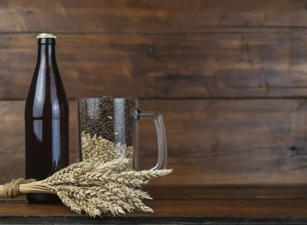 ガラスと木の板に小麦の穂とビールの瓶 — ストック写真