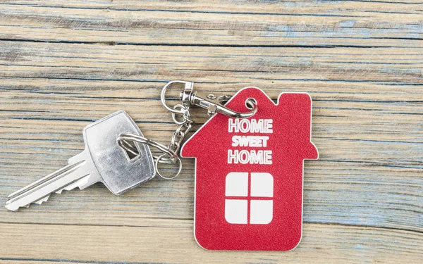 Key house with tag text home sweet home on wood background.