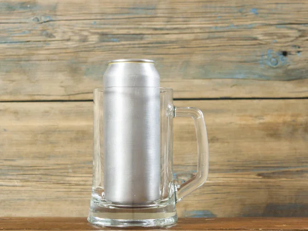 金属缶と木製の背景にビールの空マグカップ — ストック写真