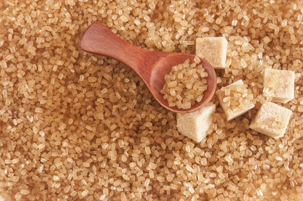 Healthy cane sugar on old wooden spoon