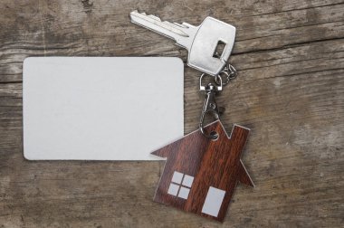 Gümüş anahtar ve ahşap arka plan üzerinde boş kartvizit. Emlak kavramı. 