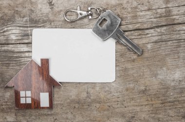 Gümüş anahtar ve ahşap arka plan üzerinde boş kartvizit. Emlak kavramı. 