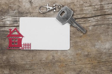 Gümüş anahtar ve ahşap arka plan üzerinde boş kartvizit. Emlak kavramı. 