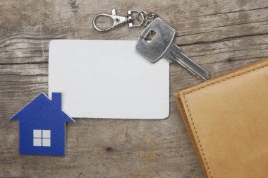 Ev simgesini ve banka kartı ve eski ahşap arka plan üstten görünüm cüzdan yakınındaki boş kağıt ile anahtar
