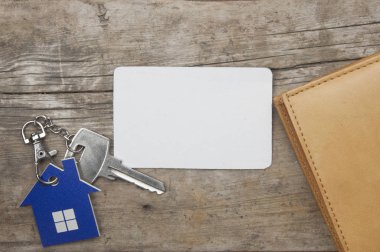 Ev simgesini ve banka kartı ve eski ahşap arka plan üstten görünüm cüzdan yakınındaki boş kağıt ile anahtar