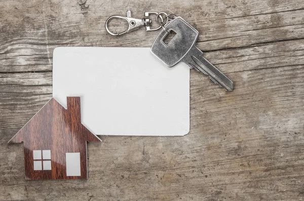 Gümüş anahtar ve ahşap arka plan üzerinde boş kartvizit. Emlak kavramı. 