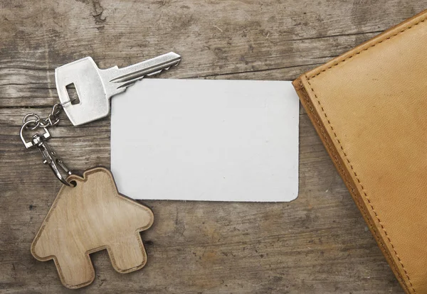 钥匙与房子图标和空白纸附近银行卡和钱包在老木背景顶视图 — 图库照片