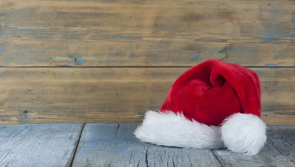 木制背景上的圣诞老人帽子 — 图库照片