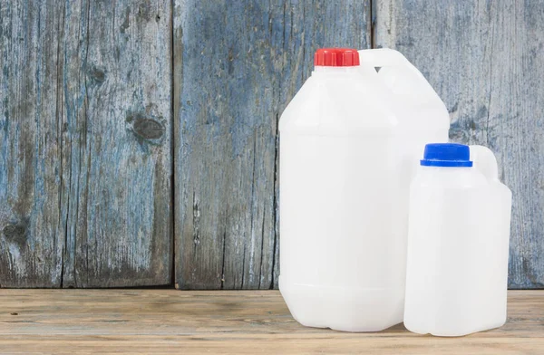 pair of plastic gallons of different configuration on wooden background