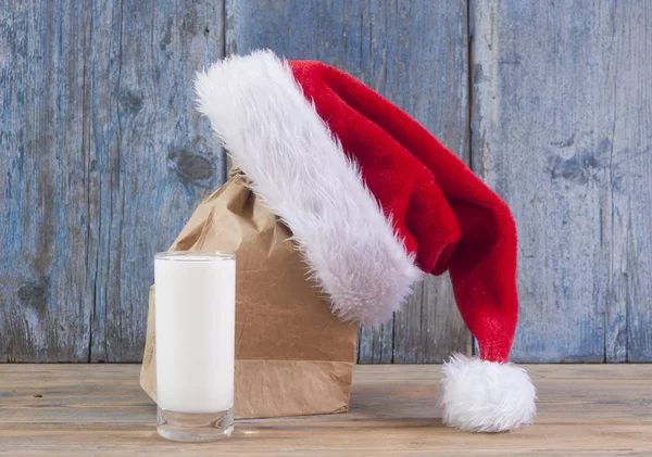 Glas Milch Und Weihnachtsmann Hut Auf Holztischhintergrund — Stockfoto