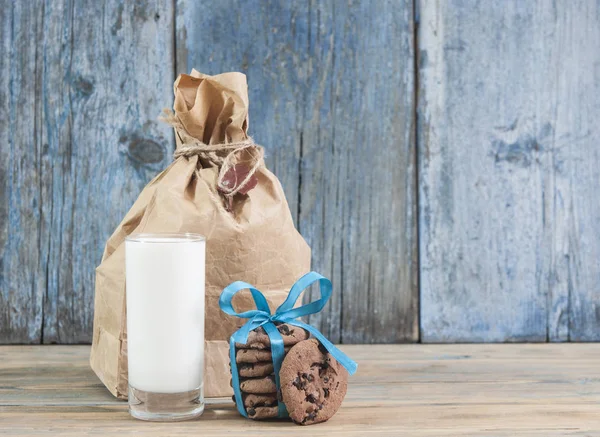 Glass of milk and chocolate chip cookies on wooden background