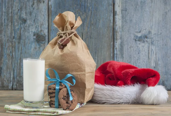 Glas Melk Smakelijke Chocoladeschilferkoekjes Kerstman Hoed Houten Tafel Achtergrond — Stockfoto