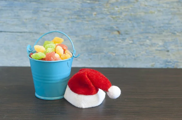 Kerstdecoratie Kerstmuts Met Kleurrijke Zoete Snoepjes Emmer Houten Achtergrond — Stockfoto