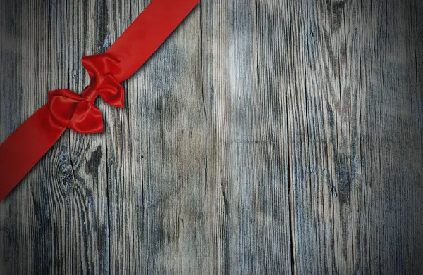 Fita vermelha decorativa e arco sobre fundo de madeira — Fotografia de Stock