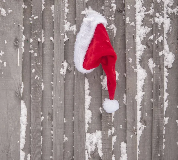 古い木製のフェンスにサンタさんの帽子 クリスマスと新年のコンセプト — ストック写真