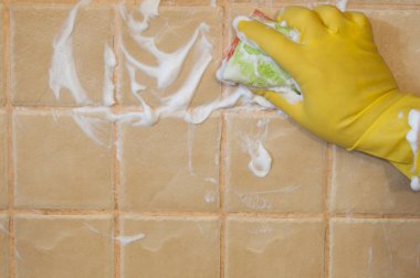 Sarı lastik eldiven giyen adamın elini karo duvara temizlik fırçalayın dönüştürmek için kullanılır. Temizlik kavramı.