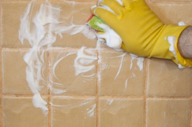 Sarı lastik eldiven giyen adamın elini karo duvara temizlik fırçalayın dönüştürmek için kullanılır. Temizlik kavramı.