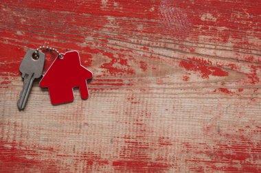 Evin anahtarları Anahtarlık Ahşap arka plan üzerinde şeklinde ev, yakın çekim. Kavramı için ana sayfa taşıyarak veya kırmızı ahşap üzerine Emlak Kiralama Emlak