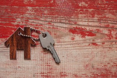Evin anahtarları Anahtarlık Ahşap arka plan üzerinde şeklinde ev, yakın çekim. Kavramı için ana sayfa taşıyarak veya kırmızı ahşap üzerine Emlak Kiralama Emlak