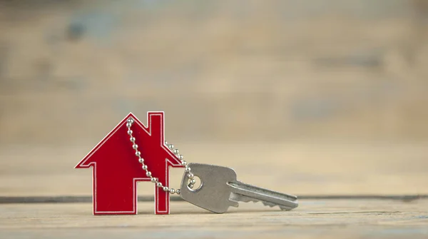 House symbol with silver keys on wood. Real estate concept