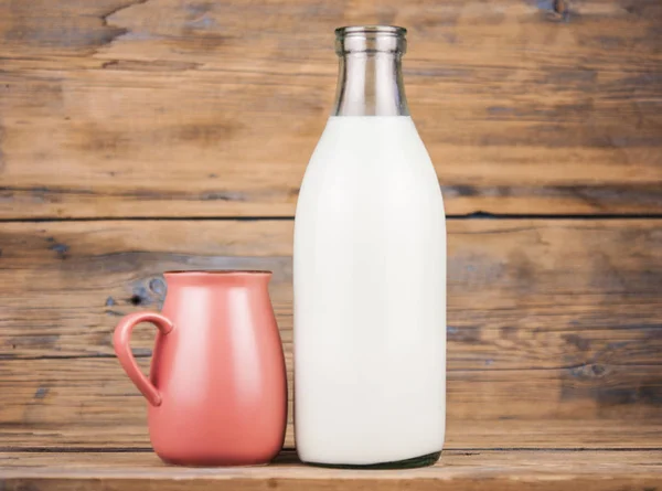 木製テーブルの上のミルクとピンクのマグカップのボトル — ストック写真