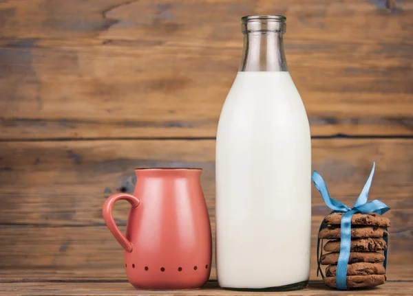 木製の背景に牛乳 ピンク マグカップのボトルとクッキーのスタック 村の朝食 — ストック写真