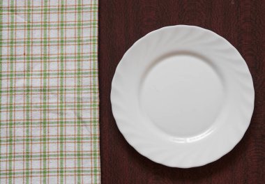 Ahşap arka plan üzerinde renkli peçete ile boş temiz beyaz plaka. Yemek daveti. Taze yemek ve hizmet hazır. Metin ve işaretleri ile kullanmak için iyi.