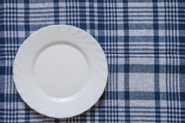 Ahşap arka plan üzerinde renkli peçete ile boş temiz beyaz plaka. Yemek daveti. Taze yemek ve hizmet hazır. Metin ve işaretleri ile kullanmak için iyi.