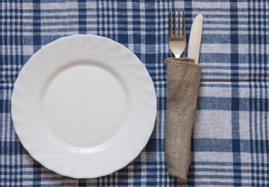 Boş temiz beyaz tabak çatal ve bıçak ahşap arka plan üzerinde renkli peçete üzerinde. Yemek daveti. Taze yemek ve hizmet hazır. Metin ve işaretleri ile kullanmak için iyi.